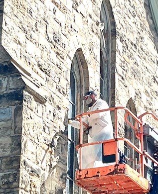 A worker on a lift at a window on the stone exterior