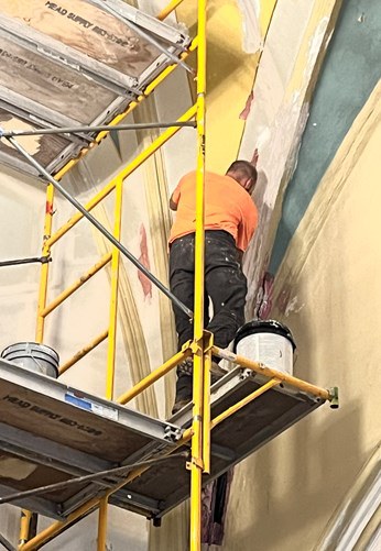 A craftsman on scaffolding repairing plaster